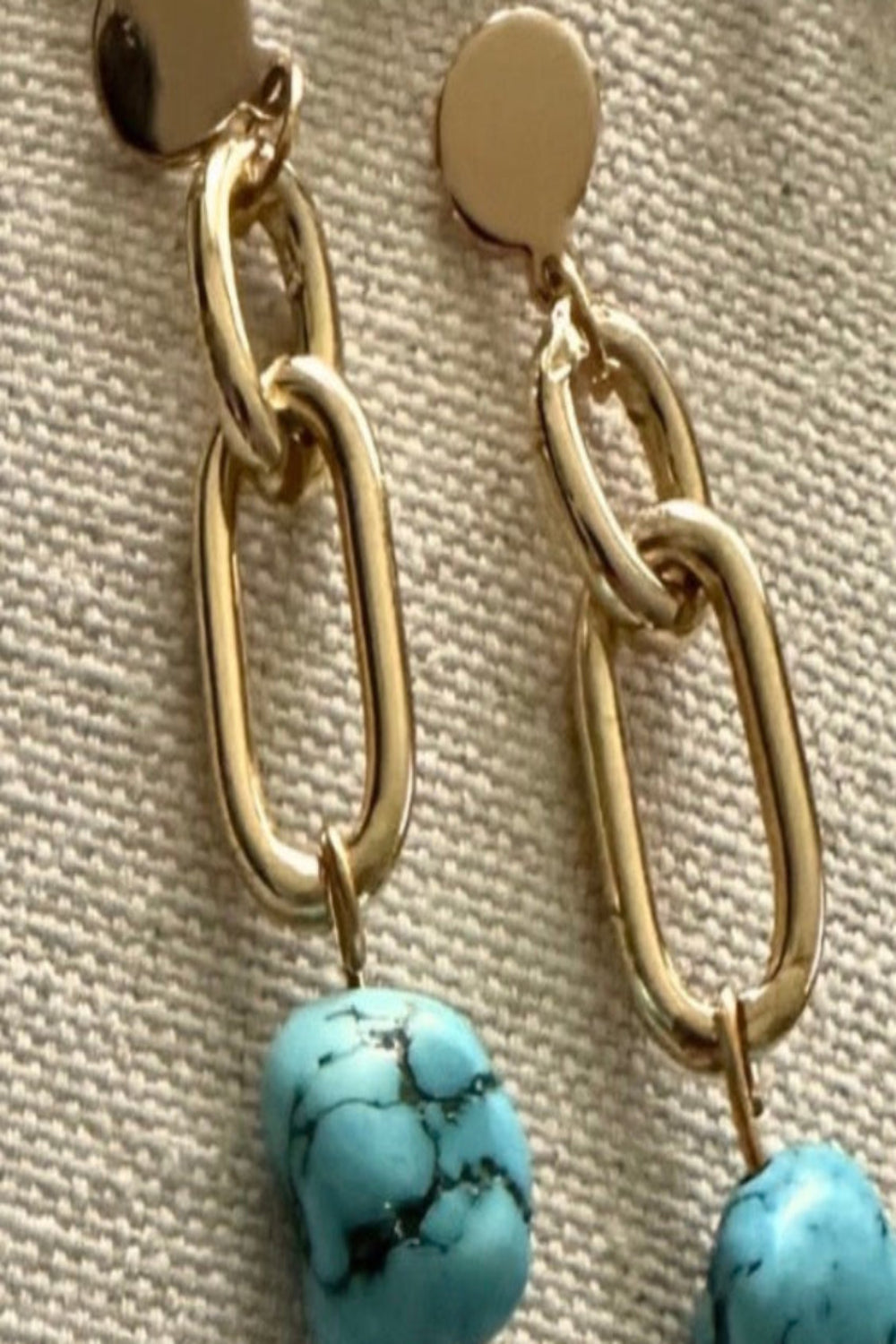 Boucles d'oreilles turquoise et chaîne dorée sur fond neutre